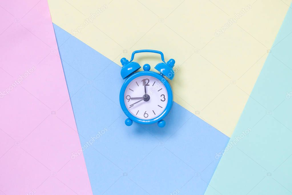 Alarm clock on multicolored pastel background minimalistic concept.