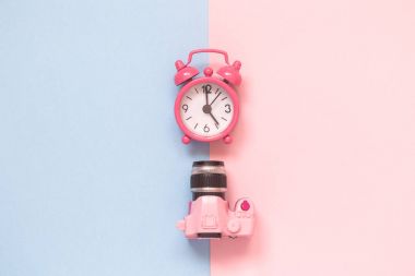 DSLR fotoğraf makinesi modeli ve çalar saat izole pastel arka plan minimalist kavramı üzerinde.