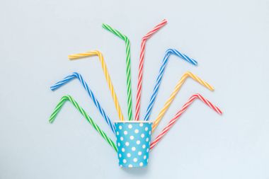 Kağıt bardak izole mavi minimalist kavramı üzerinde çok renkli içme payet ile.