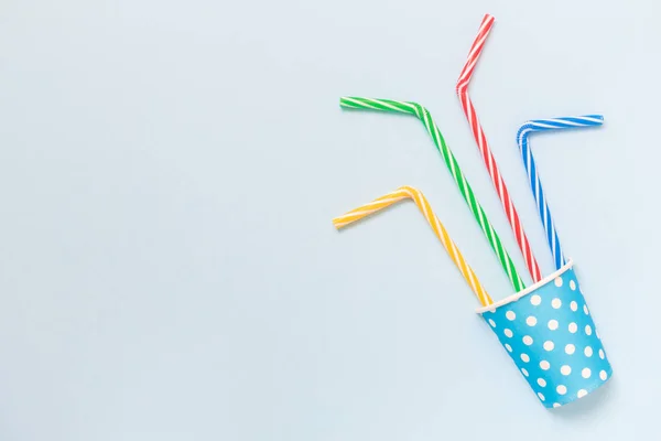 Copa de papel con pajitas de beber multicolores aislados en el concepto minimalista azul . — Foto de Stock