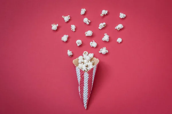 Pohled z vysokého úhlu kužele s popcorn na červeném pozadí minimalistické pojetí. — Stock fotografie