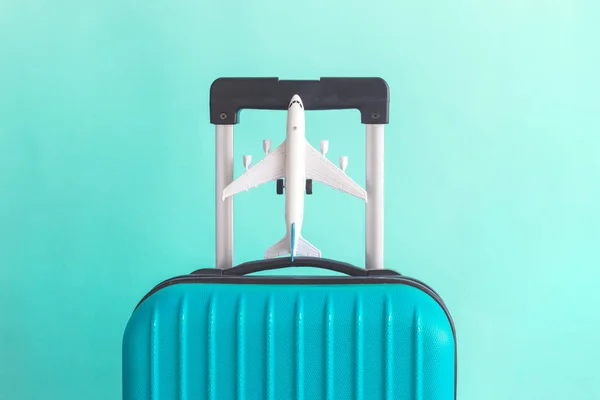 Equipaje con pequeño avión sobre fondo verde concepto de vacaciones minimalista — Foto de Stock