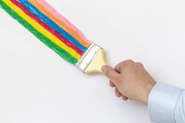 Nahaufnahme des Mannes Hand halten Pinsel mit bunten Faden isoliert auf weißem Hintergrund minimalistisches Kunstkonzept. — Stockfoto