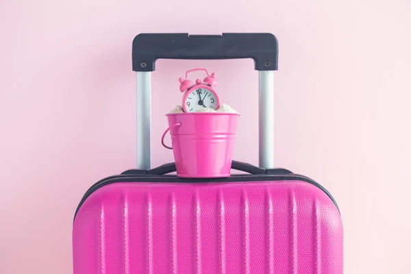 Equipaje y lata con despertador en rosa concepto de viaje de fondo . — Foto de Stock