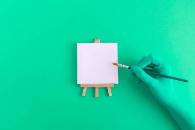 El fırça ve küçük boş sanat tuval şövale soyut kavram üzerinde yeşil renkli.