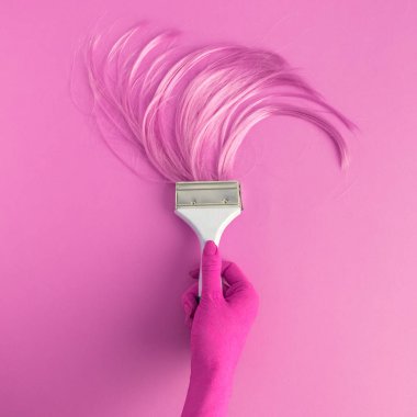 Uzun saç fırçası tutan gül renkli el