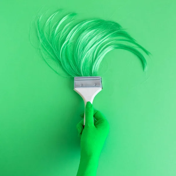 Mano de color verde sosteniendo cepillo pelo largo — Foto de Stock