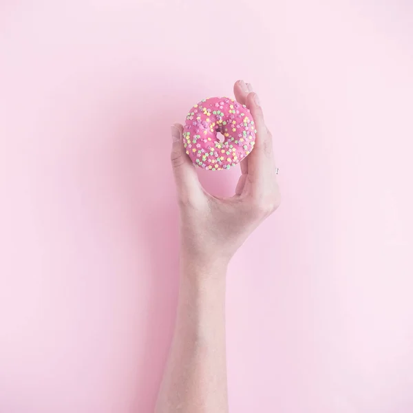 Woman hand holding small donut isolated on rose background. — Stock Photo, Image