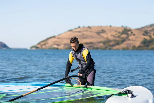 Sportowiec przygotowuje swój sprzęt do windsurfingu na płytkiej wodzie. — Zdjęcie stockowe