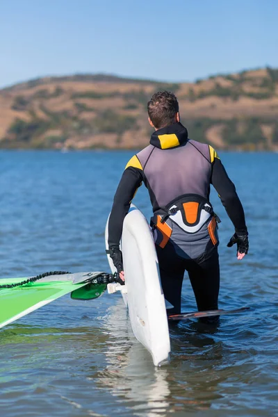 Szörfdeszkát szállító szörfös közelsége sekély vízben vitorlázva. — Stock Fotó
