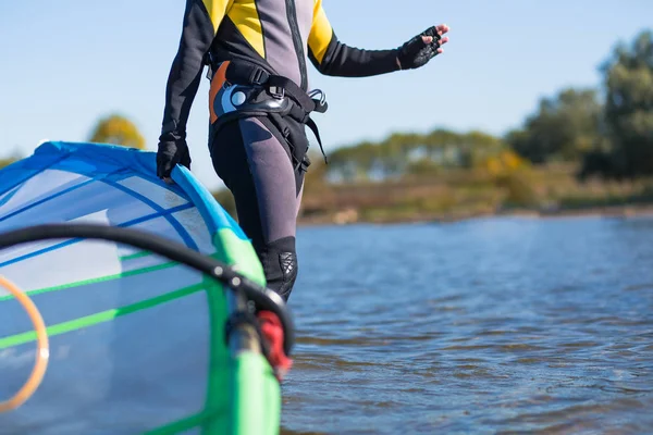 Windsurfer caminhando pela água e segurando vela . — Fotografia de Stock