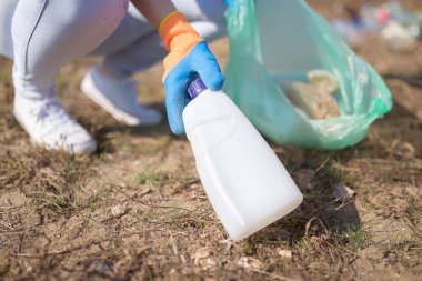 Yerden plastik çöp torbası toplayan bir kadının elini kapat. Geri dönüşüm ve ekoloji kavramı.