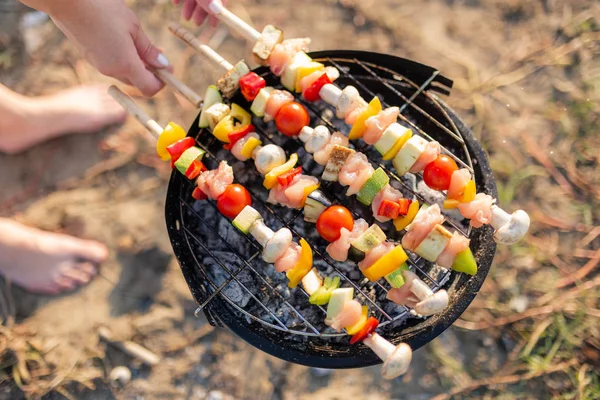 Gros plan de la jeune femelle préparant des brochettes de légumes et de poulet mélangées sur le barbecue à l'extérieur . — Photo