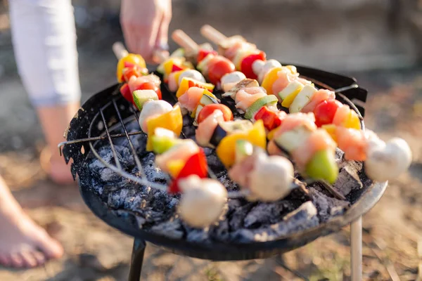 Femme main tourner la viande et les légumes tout en grillant sur le barbecue. Concept de pique-nique ou camping . — Photo