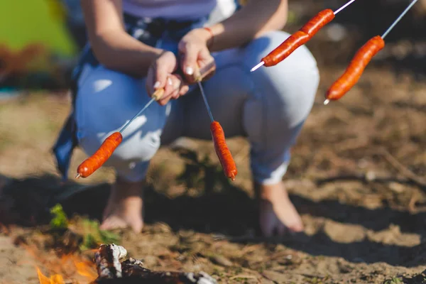 Camping dans la nature - Saucisses grillées empalées sur un bâton au-dessus du feu de camp . — Photo