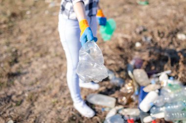 Plastik çöp şişesi toplayan bir kadının elini kapat. Ekoloji kavramı.