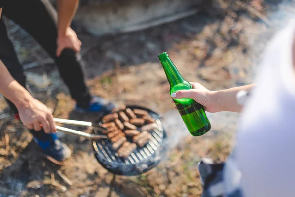 Amis déguster de la bière tout en préparant le déjeuner kebab sur barbecue à l'extérieur . — Photo