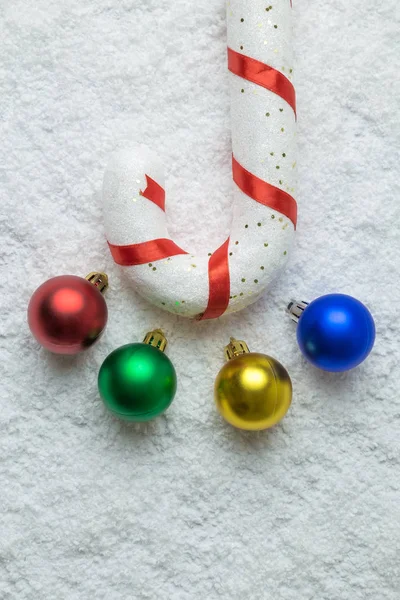 Primer plano de bastón de caramelo y bolas de Navidad multicolores sobre fondo nevado abstracto . — Foto de Stock