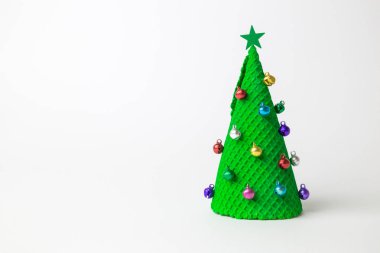 Renkli mücevherlerle süslenmiş Noel ağacı şeklinde yeşil dondurma külahı ve beyaz arka planda en az yaratıcı tatil ve yiyecek konsepti..