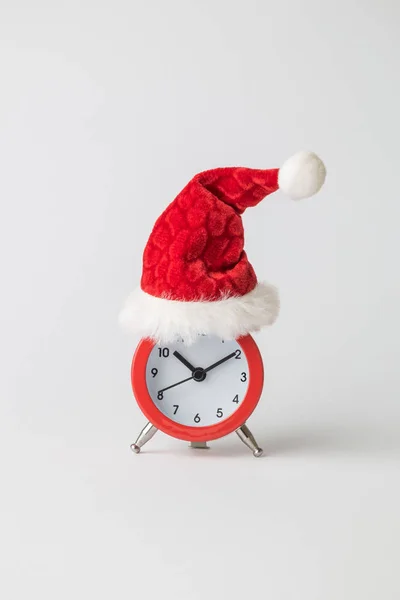 Small analog clock with Santa Claus hat abstract isolated on white. Winter season and christmas time concept. — Stock Photo, Image