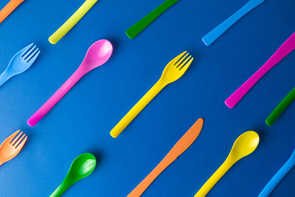 Multicolored cutlery on dark blue background abstract.