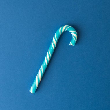 Klasik mavi arka planda düz şeker kamışı yatışı. En az yaratıcı tatlı yemek ve Noel tatili kavramları..