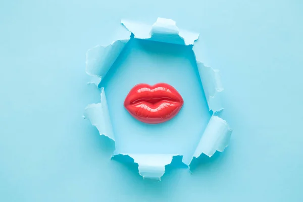 Burst buraco lábios de plástico feminino abstrato no fundo azul . — Fotografia de Stock