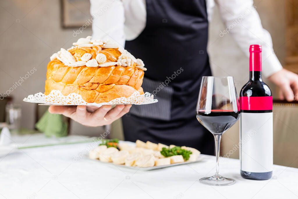 Waiter bringing orthodox homemade bread at the table.