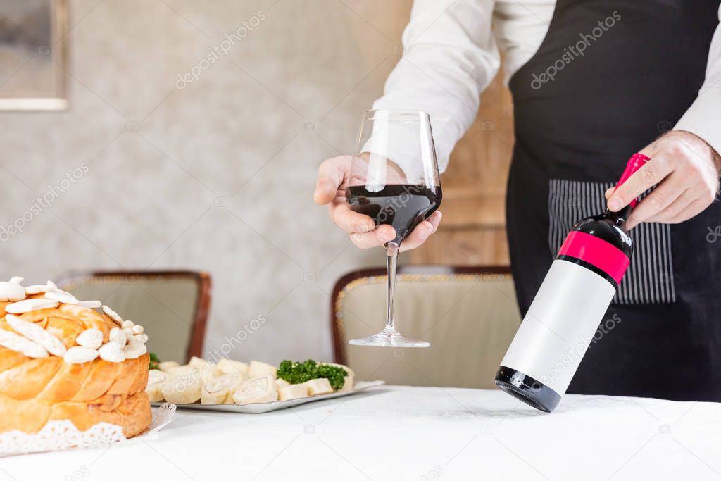 Man holding wine and decorated bread on table for celebration a saint in Orthodox faith. Serbian traditional and cultural heritage.