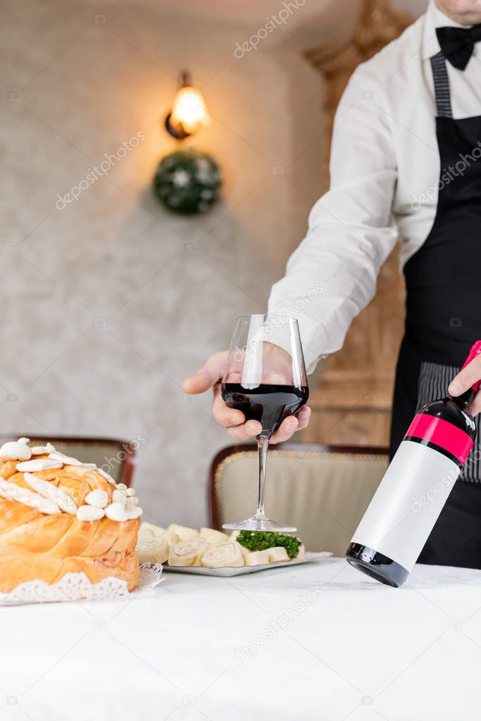 Man holding wine and decorated bread on table for celebration a saint in Orthodox faith. Serbian traditional and cultural heritage.
