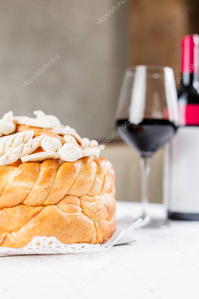 Orthodox church bread with decoration and bottle with glass of wine on table at restaurant or home.