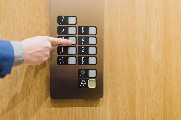 Zamknij biznesmena naciskając przycisk w nowoczesnej drewnianej i stalowej windzie. — Zdjęcie stockowe