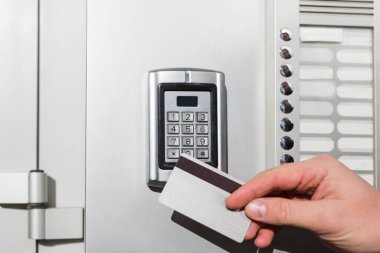 Kapı erişim kontrolü kapalı. Kilitlemek ya da açmak için elinde anahtar kartı olan bir adam..