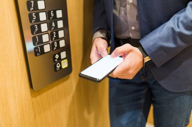 Asansörde cep telefonu kullanan tanınmayan bir işadamı.