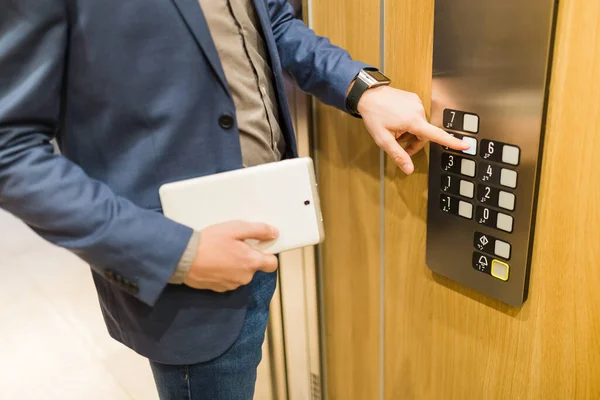エレベーターボタンを押すタブレットデバイスでビジネスマンの閉鎖 ビジネス オフィスビルミーティングコンセプト — ストック写真