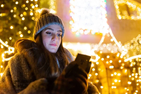 Красива Жінка Тримає Мобільний Телефон Перед Будинком Прикрашена Барвистими Вогнями — стокове фото