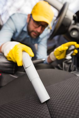 Adam oto temizleme koltuğunu elektrikli süpürgeyle kapat..