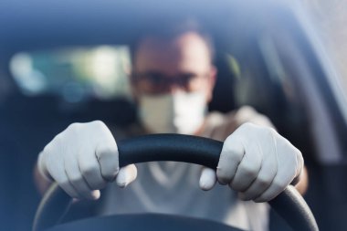 Yüz maskeli ve tıbbi eldivenli sürücü portresi, koronavirüs salgını konsepti.