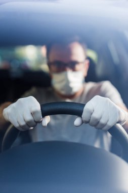 Koruyucu maskeli, elleri lastik eldivenli, direksiyonlu, bakteri ve virüs enfeksiyonundan korunan sürücüyü kapatın..