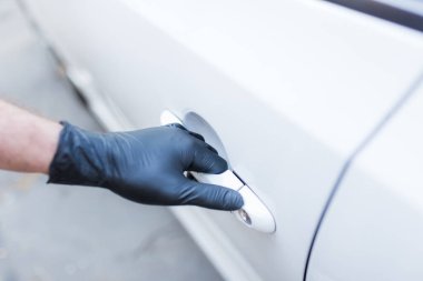 Cerrahi koruyucu eldivenli sürücü arabanın kapısını açıyor. Coronavirus önleme.