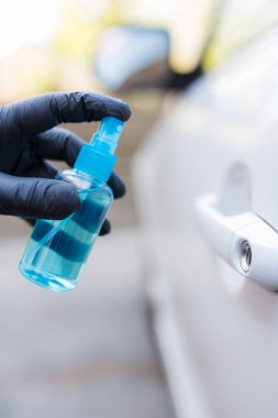 Koruyucu eldivenli, antibakteriyel sprey ya da dezenfektan sıkan bir sürücü..