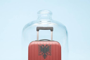 Arnavutluk bayrağının karantinada tasarlandığı çanta, asgari yaratıcı koronavirüs seyahat kısıtlaması kavramı.