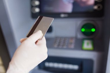 ATM 'nin yanında kredi kartı tutan tıbbi koruyucu eldiven verin. Covid-19 konsepti.