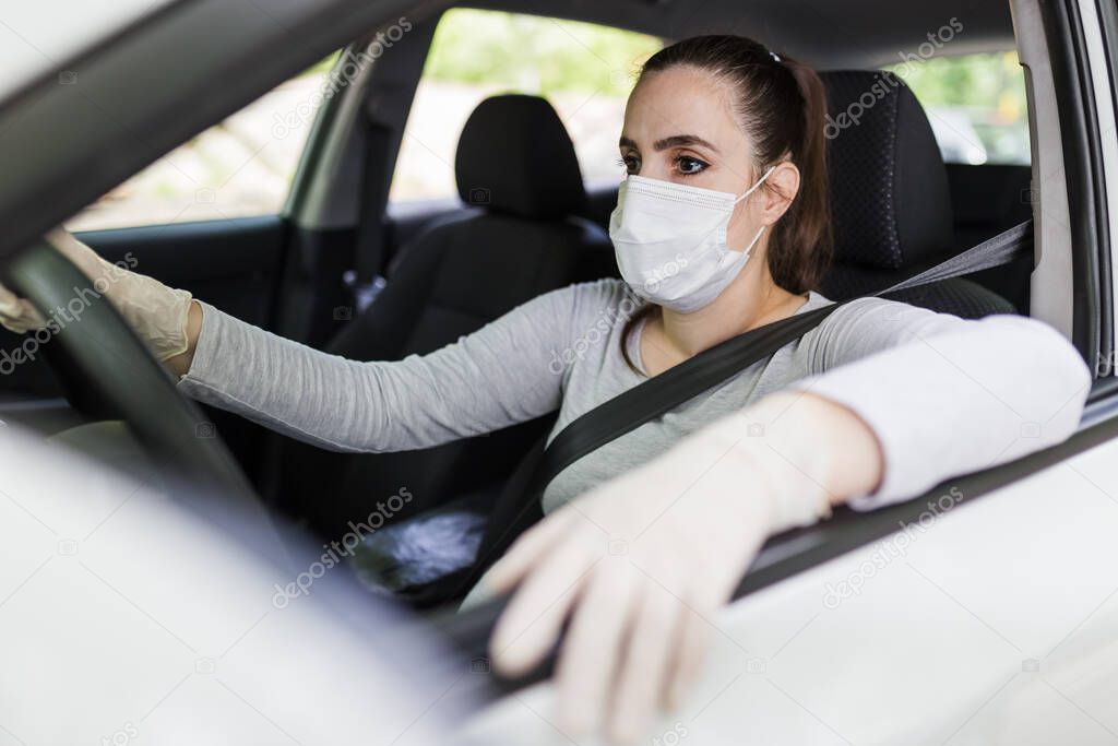 Close up of female driver in protective mask with hands in rubber gloves on steering wheel, covid-19 protection from bacteria and virus infection.