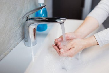 Banyoda musluğun altında ellerini yıkamak. Hijyen kavramı.