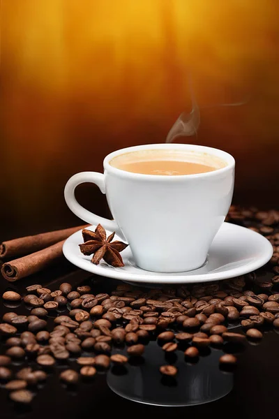 Kahve çekirdekleri ile karanlık bir arka plan üzerinde beyaz kahve fincanı