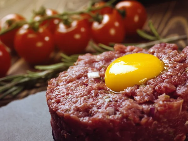 Beef tartar with an egg on a stone plate.