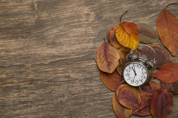 Gamla klocka på en bakgrund av gula blad — Stockfoto
