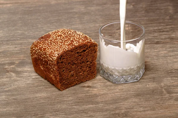 Delicioso leite de pão preto em um fundo de madeira — Fotografia de Stock