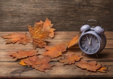 Sonbahar yapraklarıyla dekore edilmiş eski ahşap arka plandaki saat